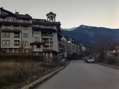 a building on the side of a street with a mountain at Apartment Melania in Complex Royal Towers in Bansko