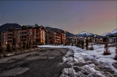 a snowy street in a city with buildings and mountains at St Ivan Ski and Spa Studio in Bansko