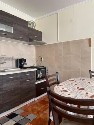 a kitchen with a table with chairs and a kitchen with a counter at Чудесно място за нощувки в Пампорово in Pamporovo