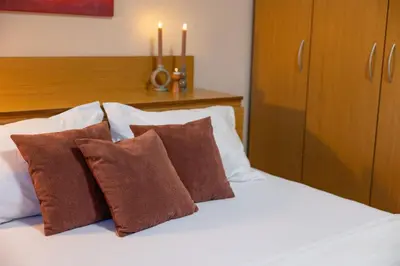 a white bed with brown pillows and candles on it at Groovy Olive Apartment in Troyan
