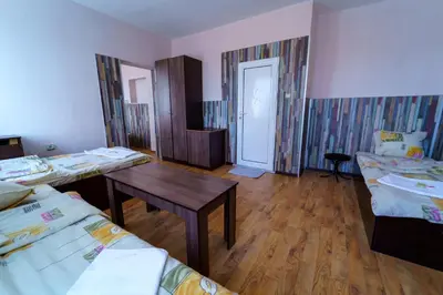 a room with two beds and a table and a door at Вила Горски Кът in Yavrovo