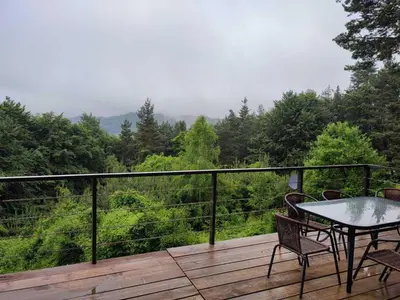 a wooden deck with a table and chairs on it at Вила Горски Кът in Yavrovo