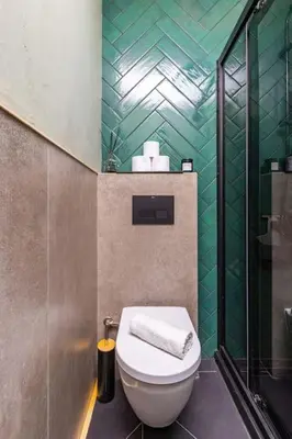a bathroom with a toilet and a green tiled wall at Casa di Marko Stylish apt in the Center in Plovdiv
