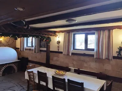 a dining room with a table and chairs and a bed at Mira Guest House in Dobrinishte