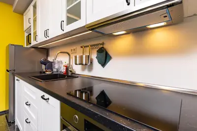 a kitchen with white cabinets and a black counter top at Bright Windowed Studio 10 mins to the City Centre by Flat Mаnager in Plovdiv