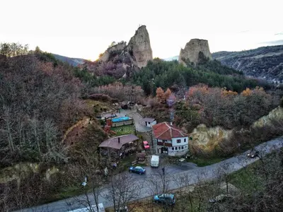 a house on a hill with a castle in the background at Melnik Pyramids Guesthouse in Zlatkov Chiflik