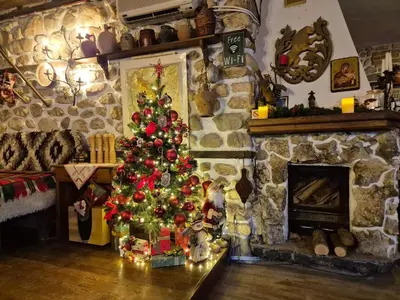 a christmas tree in a living room with a fireplace at Melnik Pyramids Guesthouse in Zlatkov Chiflik