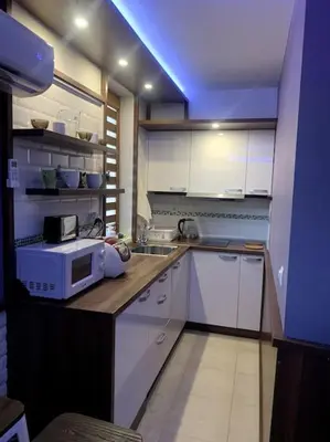 a kitchen with white cabinets and a blue light at Уютная студия Green Life E 04 in Bansko