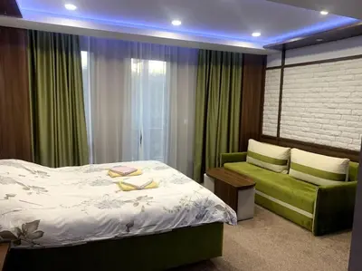 a bedroom with a bed and a green couch at Уютная студия Green Life E 04 in Bansko
