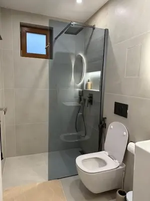 a bathroom with a toilet and a glass shower at Cozy design 1 bedroom apartment in Bansko