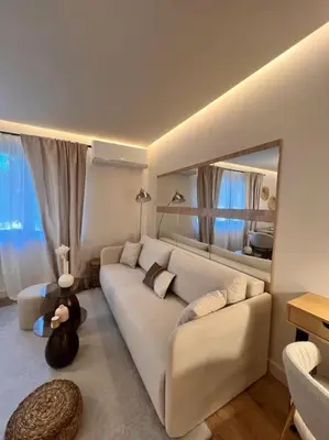 a living room with a white couch and a mirror at Cozy design 1 bedroom apartment in Bansko