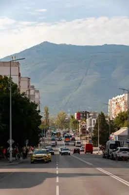 a city street with cars driving down a street with a mountain at The Mirror Apartment in Sofia