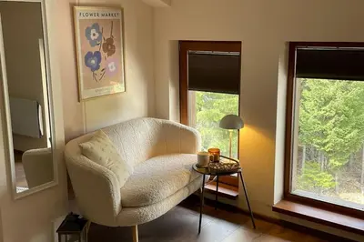 a living room with a chair and a table and two windows at Studio Béni in Smolyan