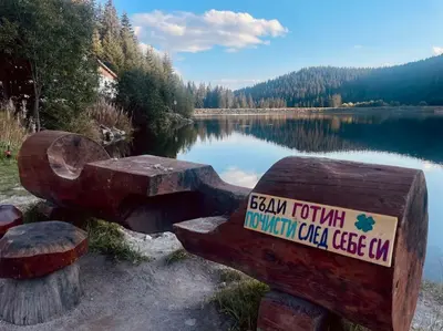 a sign on a bench next to a lake at Studio Béni in Smolyan