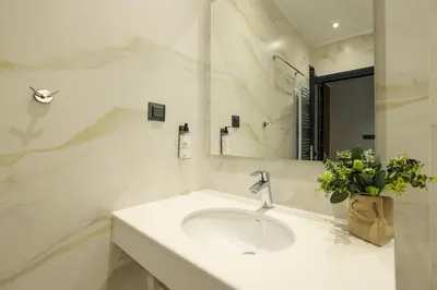 a white bathroom with a sink and a mirror at Lavalliere Hotel & Villas in Sarnitsa