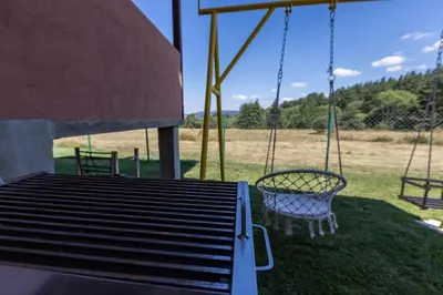 a swing set with two chairs in a yard at Къща за гости Дар in Batak