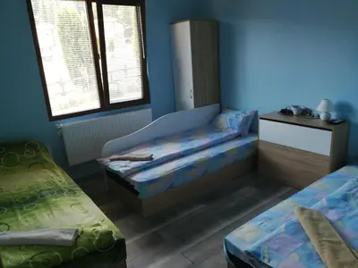 a room with two beds and a desk and two windows at Къща за гости Дар in Batak