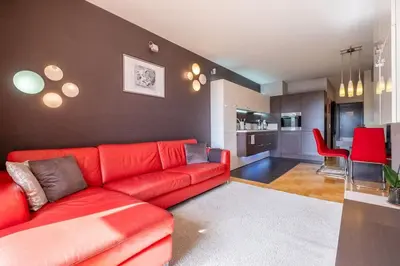 a living room with a red couch and a kitchen at iLonka's Home 1 BDR with Workspace and Terrace in Sofia