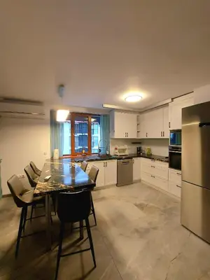 a kitchen with a table and chairs and a refrigerator at 4-bedrooms luxury apartment very close to ski lift in Bansko
