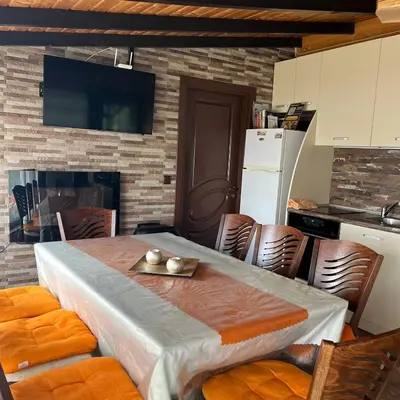 a kitchen with a table and chairs and a kitchen with a tv at Вила Сънсет 1 in Dospat