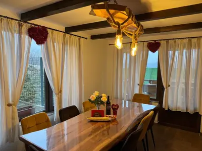 a dining room table with chairs and a large window at Вила Сънсет 2 in Dospat