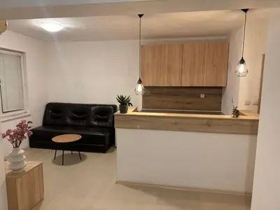 a living room with a black couch and a kitchen at Апартамент за гости ''ЗДРАВЕ'' in Kyustendil