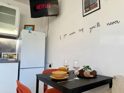 a kitchen with a table with a television on a wall at Comfy Studio by Cosher in Sofia