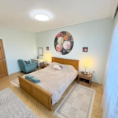 a bedroom with a bed and a blue chair at Апартамент ГТ in Plovdiv