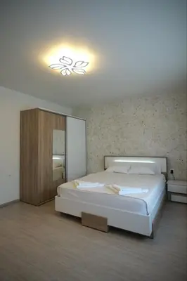 a bedroom with a large white bed and a light at Апартамент за гости Симона in Smolyan