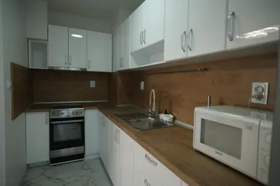 a kitchen with white cabinets and a sink and a microwave at Апартамент за гости Симона in Smolyan