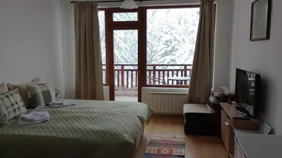 a bedroom with a bed and a television and a balcony at Студио 36 - Семирамида, Боровец in Borovets