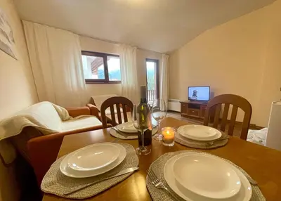 a dining room with a table with plates and wine glasses at Mountain view 1-bedroom apartment few steps from ski piste and Gondola lift in Bansko