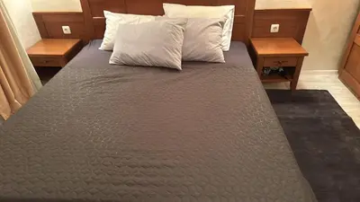 a bed in a room with two nightstands and two tables at English Apartments 2 in Bansko