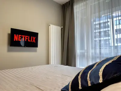 a bedroom with a bed with a netflix sign next to a window at Apartment with Free Underground Parking by COSHER in Sofia