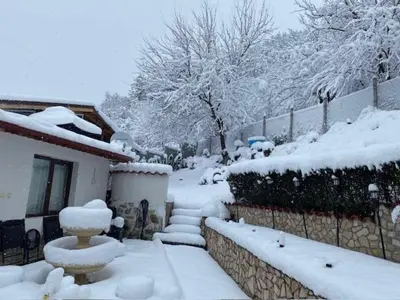 a yard covered in snow next to a house at Villa Popovi in Simitli