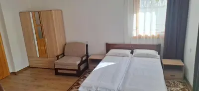 a bedroom with two beds and a chair and a window at Студио Вили in Smolyan