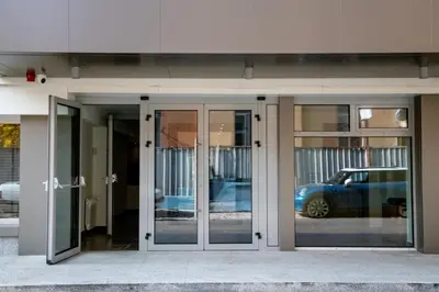a building with glass doors with a car in the reflection at BG Hotel in Sofia