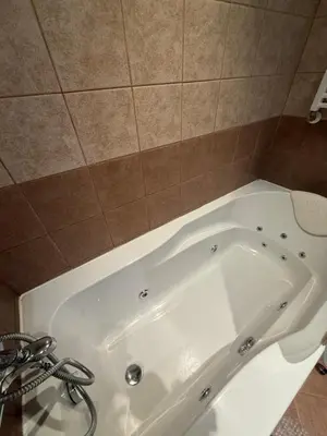 a white bath tub in a bathroom with a tile wall at Prime location one bed apartment with hydro bath in Royal Plaza in Borovets