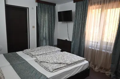 a bedroom with two beds and a window with curtains at Къща за Гости БАРБЕЛ in Golyam Izvor