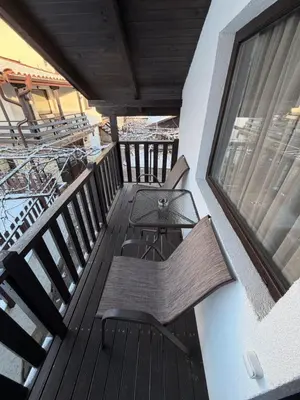a wooden balcony with a table and a window at Къща за Гости БАРБЕЛ in Golyam Izvor