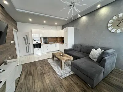 a living room with a couch and a clock on the wall at Royalton Résidence in Plovdiv
