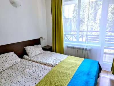 a bedroom with two beds and a large window at STRIM Apartment 406 Stream Resort, Pamporovo in Pamporovo
