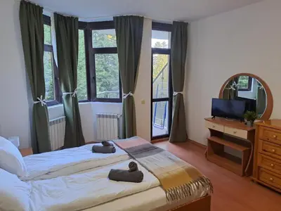 a bedroom with two beds and a television and windows at FLORA Apartment Hotel STUDIO 411 in Borovets