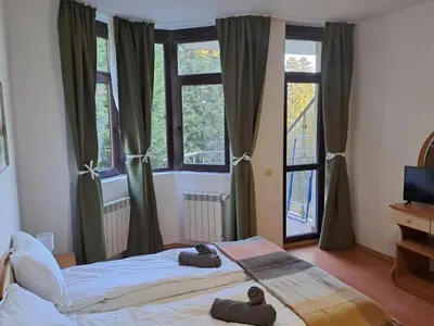 a bedroom with two beds in front of windows at FLORA Apartment Hotel STUDIO 411 in Borovets
