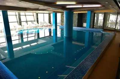 a large swimming pool with blue columns in a building at Elegant Apartment Ski Access Premium Spa in Bansko