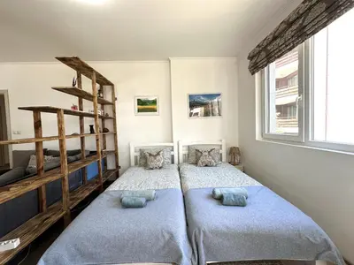 a bedroom with two beds and a large window at Cosy 2-bedroom apartment near the ski road Bansko in Bansko