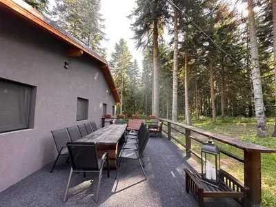 a deck with a wooden table and chairs on a house at Stylish Alpine Ski Chalet Tirol in Borovets
