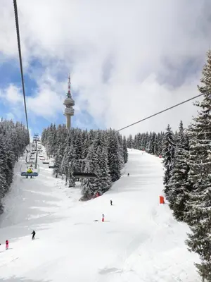 a ski lift with people skiing down a snow covered slope at Sun Stream Apartment in Pamporovo