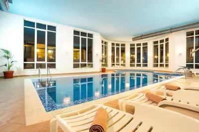 a swimming pool in a house with white chairs at Sun Stream Apartment in Pamporovo
