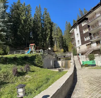 a building on a hill next to a building at Alenik Private Apartment -The Stream Resort Pamporovo in Pamporovo
